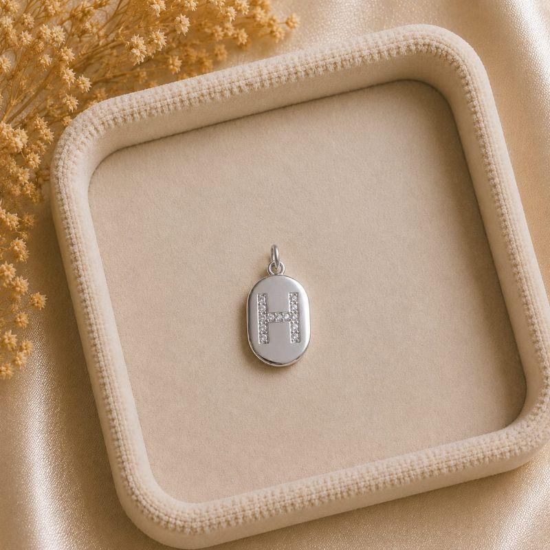 Pingente Letra Oval Cravejada H (19x10mm)