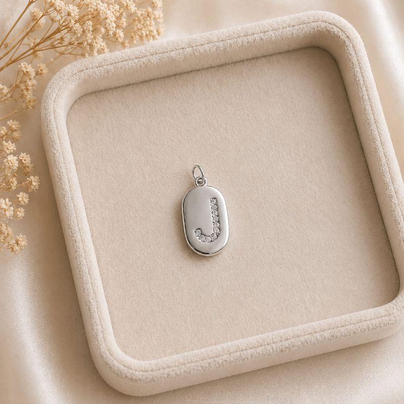 Pingente Letra Oval Cravejada J (19x10mm)