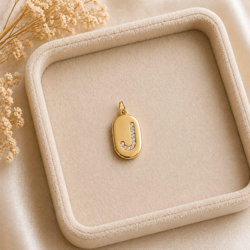 Pingente Letra Oval Cravejada J (19x10mm)